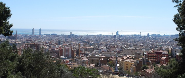 Panoramic view over Barcelona from above, showing the Eixample grid, the Sagrada Família and the Mediterranean beyond