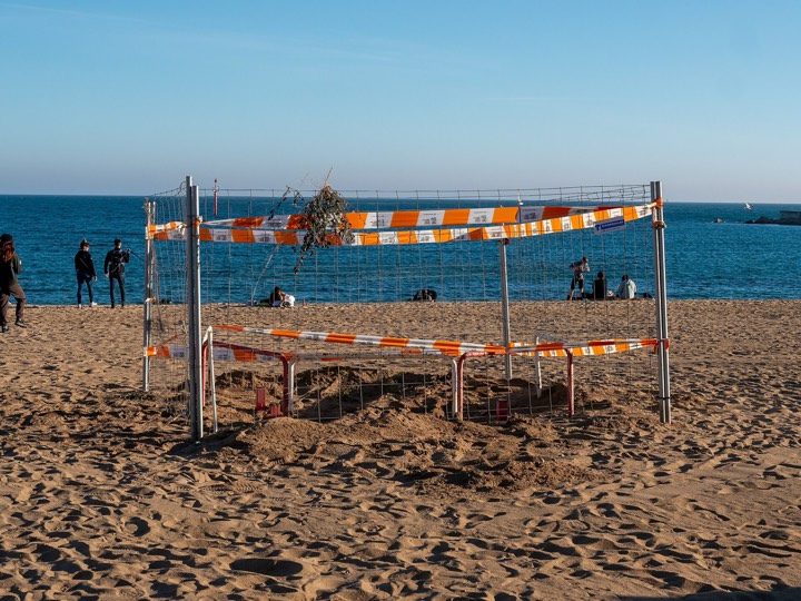 Barceloneta beach crowded with bathers in summer, with the seafront promenade and Barcelona buildings behind